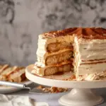 caramel cloud cake on a cake stand with a spatula pulling out a slice CARAMEL CLOUD CAKE RECIPE